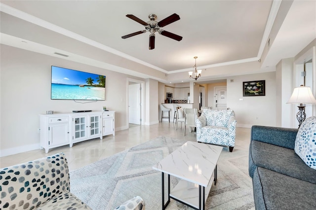 living area with ceiling fan with notable chandelier, ornamental molding, visible vents, a raised ceiling, and baseboards