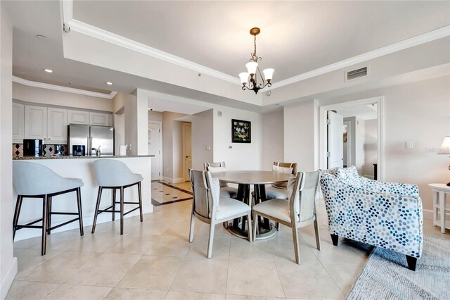 dining area with a tray ceiling, an inviting chandelier, crown molding, and visible vents