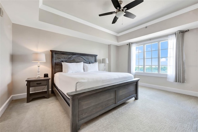 carpeted bedroom with ceiling fan, a tray ceiling, and crown molding