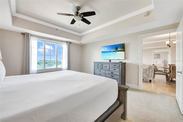 carpeted bedroom with ceiling fan with notable chandelier and a raised ceiling