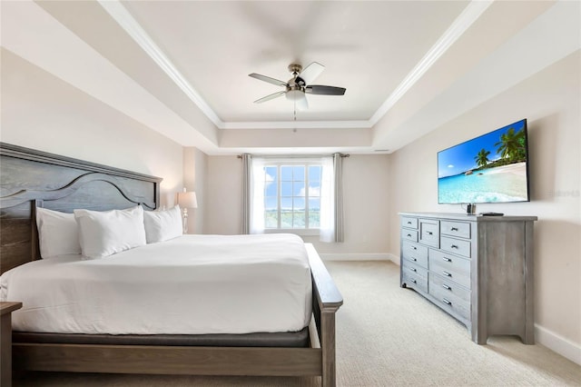bedroom with light colored carpet, a raised ceiling, baseboards, and ornamental molding