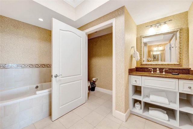 bathroom with a relaxing tiled tub, vanity, and tile patterned flooring