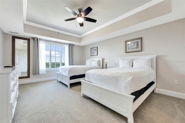 bedroom with a ceiling fan, baseboards, ornamental molding, a raised ceiling, and light colored carpet