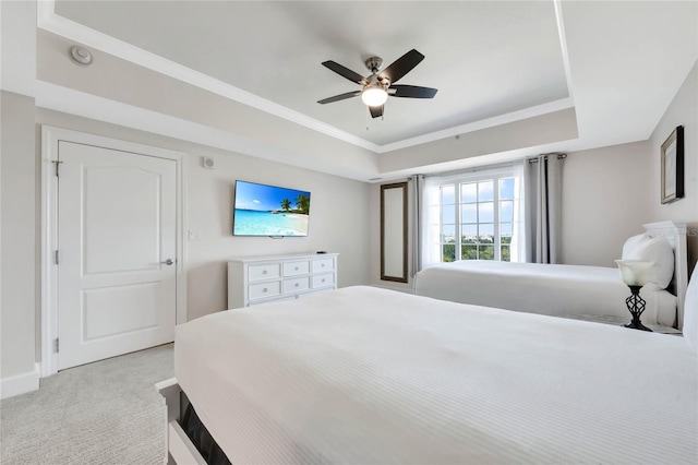 carpeted bedroom with a raised ceiling and ceiling fan