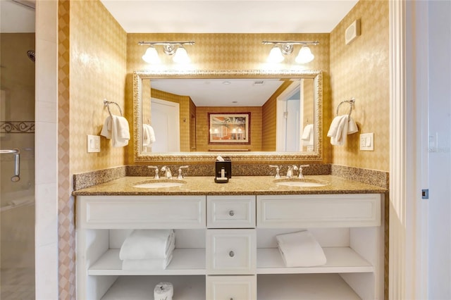 bathroom featuring a sink, double vanity, a shower, and wallpapered walls