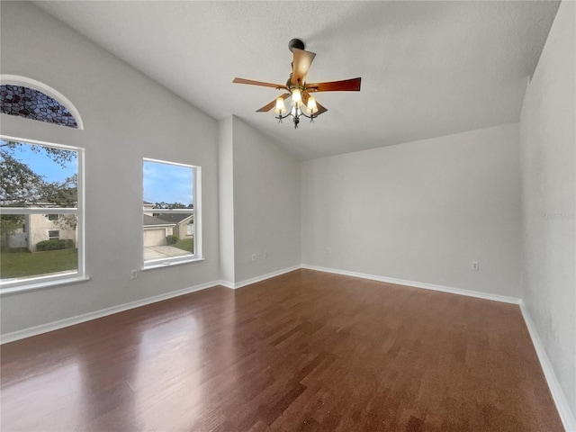 empty room featuring lofted ceiling, dark hardwood / wood-style flooring, a textured ceiling, and ceiling fan