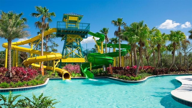 view of pool with a water slide and a playground