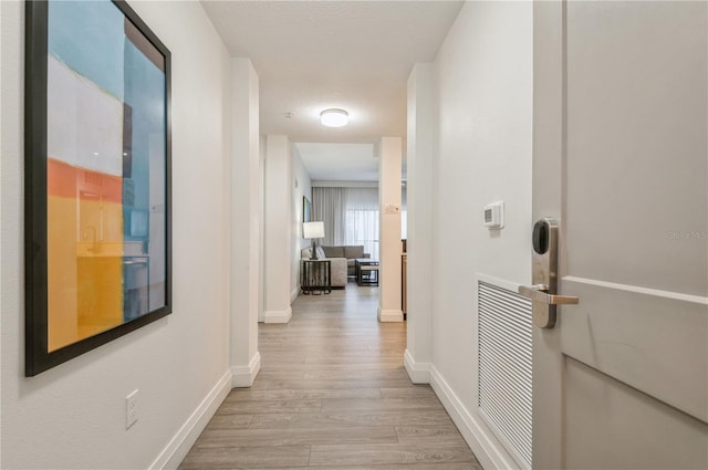 hall with light hardwood / wood-style flooring and a textured ceiling