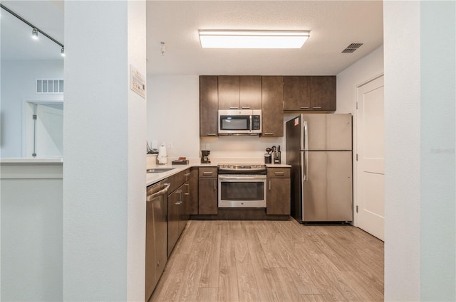 kitchen featuring dark brown cabinetry, light hardwood / wood-style floors, and appliances with stainless steel finishes