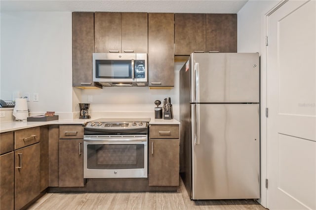 kitchen with dark brown cabinets, appliances with stainless steel finishes, and light wood-type flooring