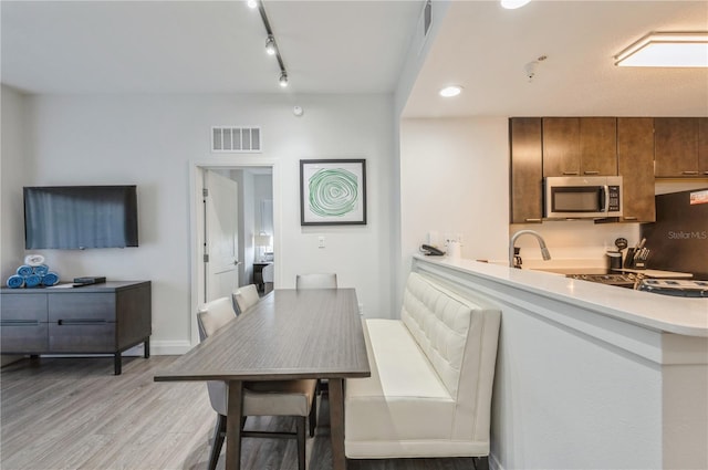 dining space with light hardwood / wood-style flooring and rail lighting