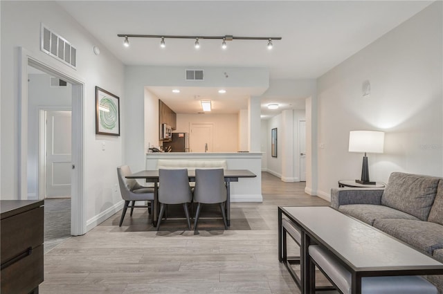 dining area with light hardwood / wood-style floors and rail lighting