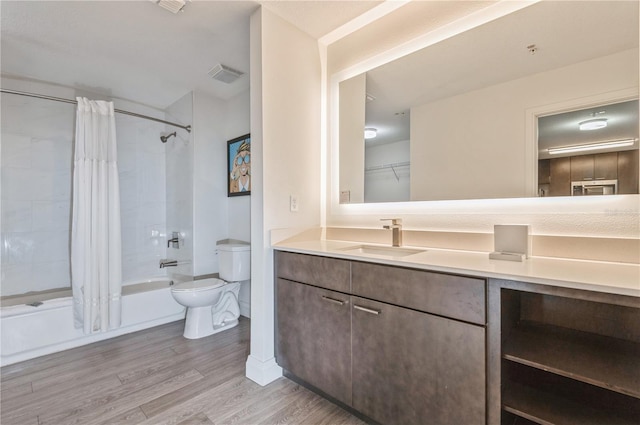 full bathroom featuring toilet, vanity, hardwood / wood-style floors, and shower / tub combo