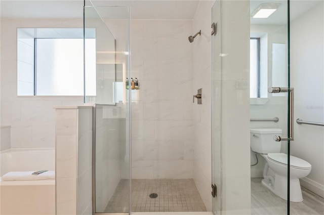 bathroom featuring toilet, a shower with door, and a healthy amount of sunlight