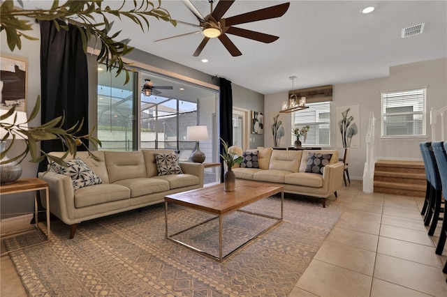 living room with light tile floors and ceiling fan with notable chandelier