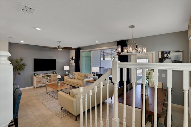 living room featuring light tile flooring and ceiling fan with notable chandelier