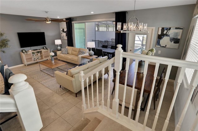 tiled living room featuring ceiling fan with notable chandelier