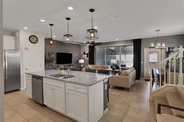 kitchen featuring decorative light fixtures, a center island with sink, appliances with stainless steel finishes, white cabinets, and sink