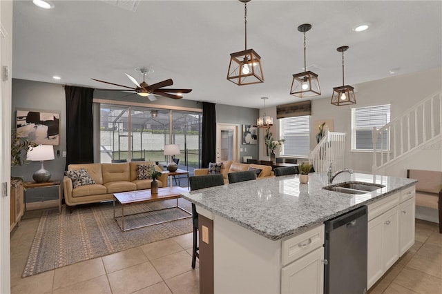 kitchen featuring decorative light fixtures, white cabinetry, ceiling fan with notable chandelier, sink, and a center island with sink