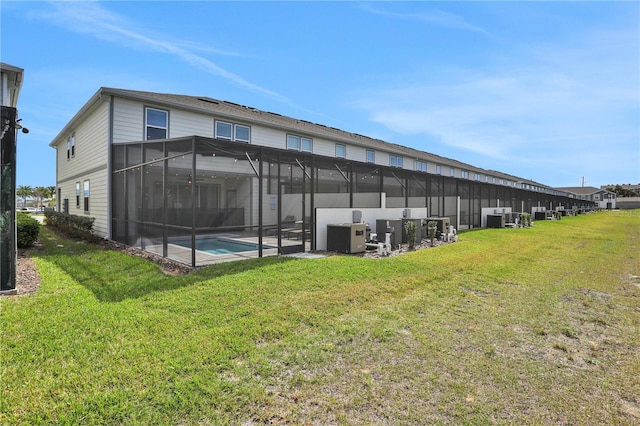 rear view of house featuring glass enclosure, central AC, a yard, and a patio