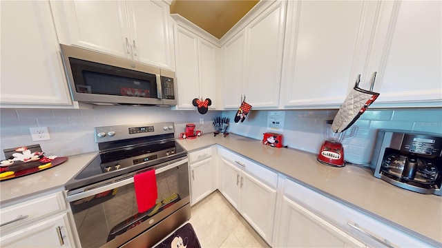 kitchen featuring tasteful backsplash, stainless steel appliances, light tile flooring, and white cabinetry