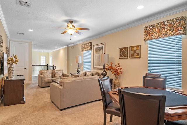 dining area featuring ceiling fan, a textured ceiling, light carpet, and crown molding