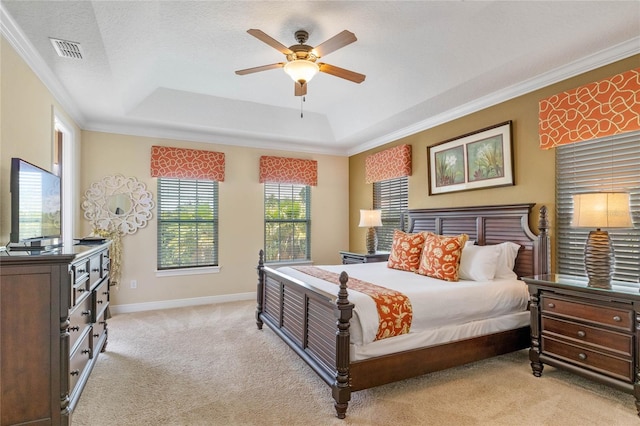 carpeted bedroom with ceiling fan, ornamental molding, and a tray ceiling