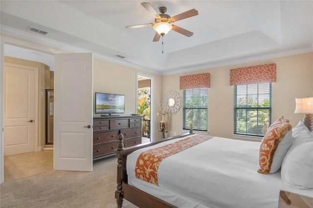 bedroom featuring ceiling fan, crown molding, a tray ceiling, and light colored carpet