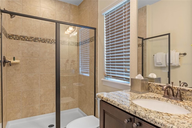 bathroom with toilet, large vanity, and a shower with shower door