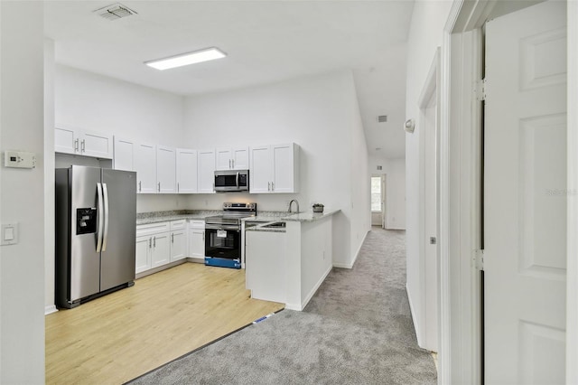 kitchen with white cabinetry, sink, light stone counters, light hardwood / wood-style flooring, and appliances with stainless steel finishes