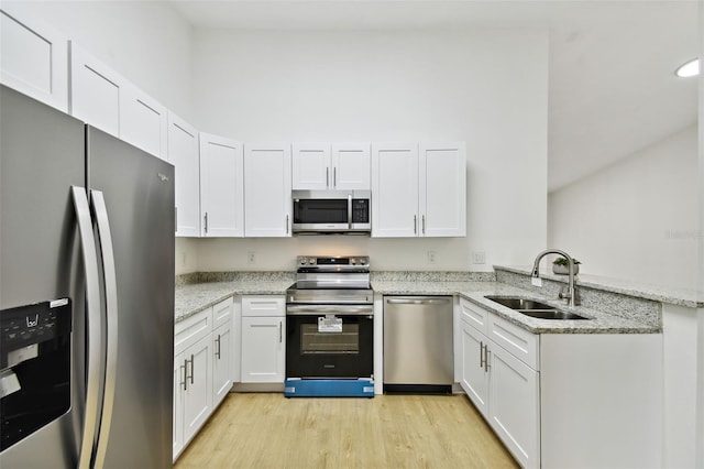 kitchen with sink, light stone countertops, appliances with stainless steel finishes, white cabinetry, and kitchen peninsula