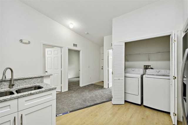 laundry area featuring washing machine and dryer, light hardwood / wood-style floors, and sink