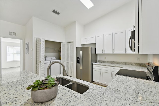 kitchen with white cabinets, sink, appliances with stainless steel finishes, light stone counters, and washer / clothes dryer