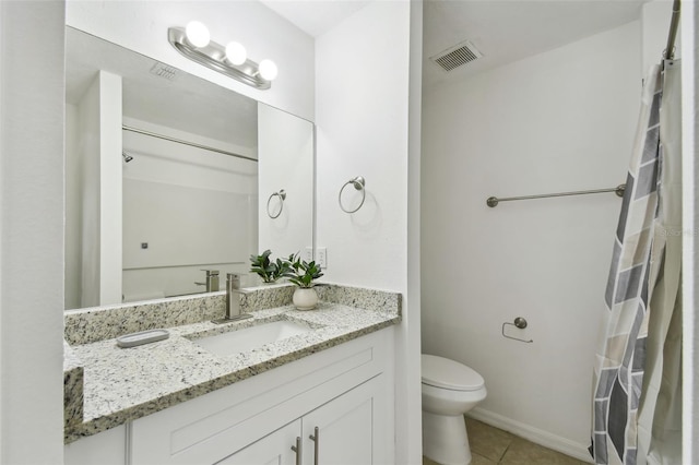 bathroom with toilet, vanity, and tile patterned floors