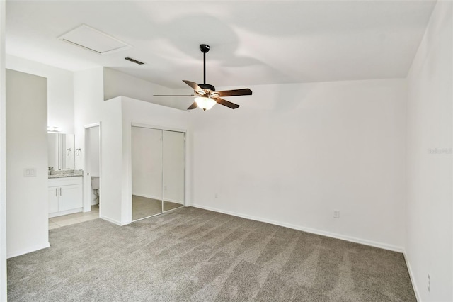 unfurnished bedroom with light carpet, a closet, ceiling fan, and ensuite bathroom