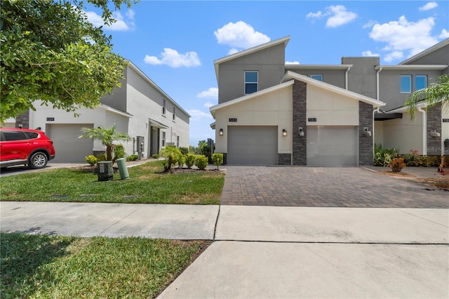 view of front of property featuring driveway, an attached garage, stucco siding, stone siding, and a front lawn