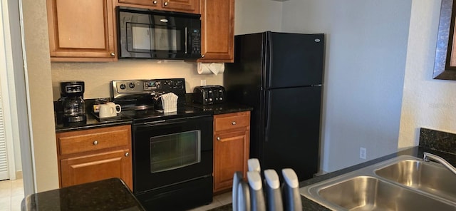 kitchen featuring light tile floors, dark stone countertops, black appliances, and sink