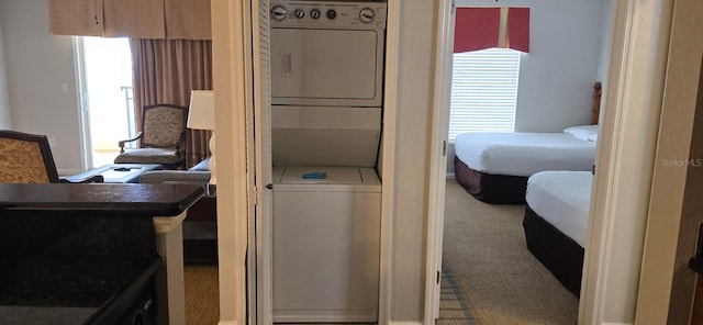 bedroom with stacked washer / drying machine and carpet