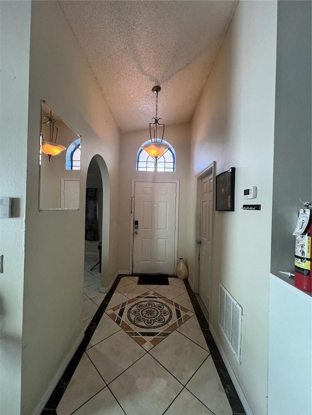 doorway featuring a textured ceiling and light tile floors