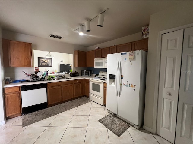 kitchen featuring rail lighting, white appliances, sink, and light tile floors