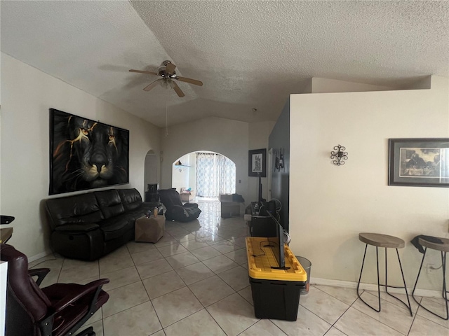 living room featuring vaulted ceiling, a textured ceiling, light tile flooring, and ceiling fan