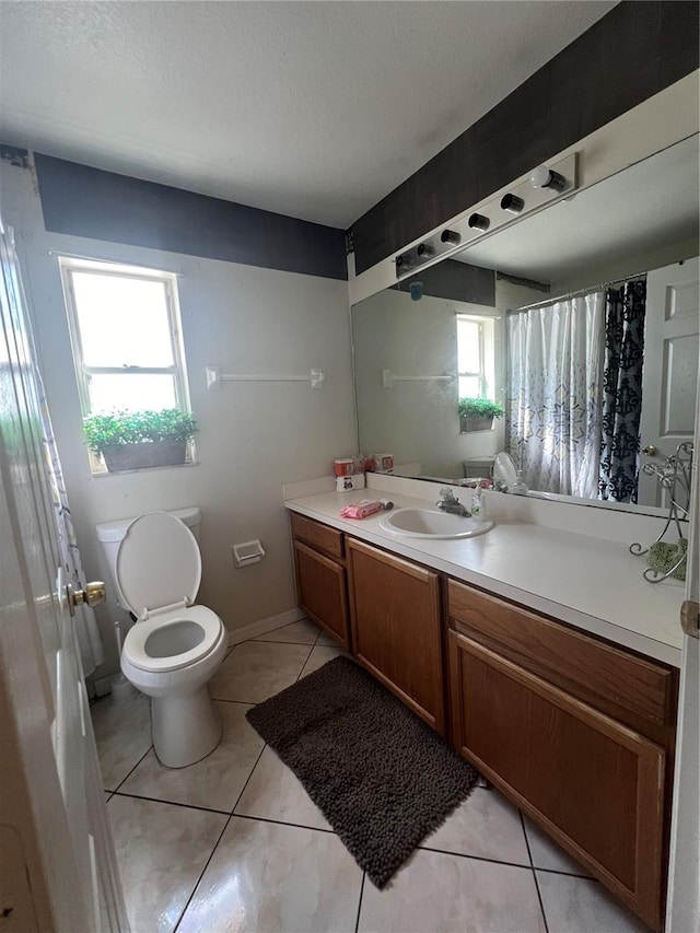 bathroom featuring toilet, tile flooring, a healthy amount of sunlight, and vanity