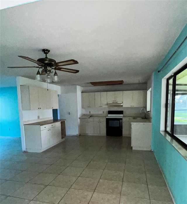 kitchen with ceiling fan, light tile floors, sink, stove, and white cabinetry