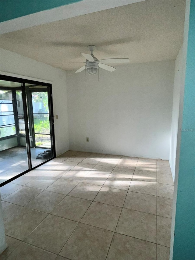 empty room with a textured ceiling, ceiling fan, and light tile floors