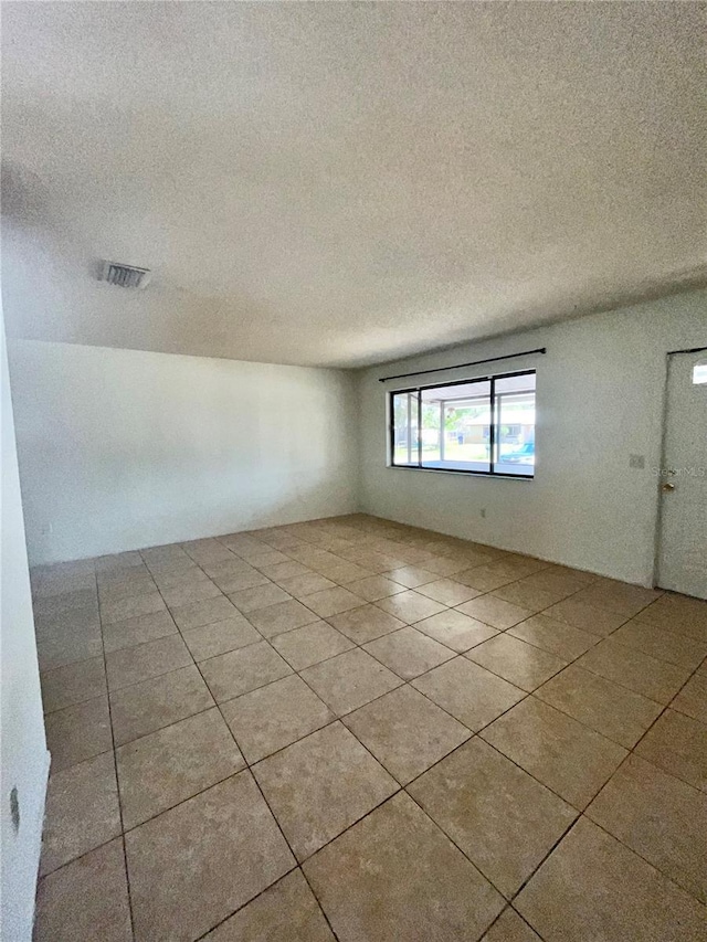 empty room featuring visible vents, a textured ceiling, and tile patterned floors