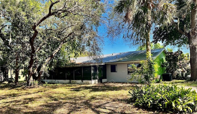 back of house featuring metal roof, a sunroom, and stucco siding