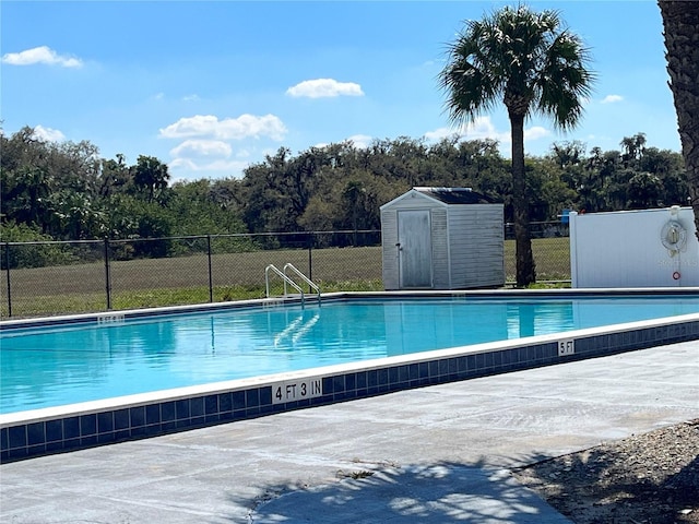 community pool with an outbuilding, a patio, a storage unit, and fence