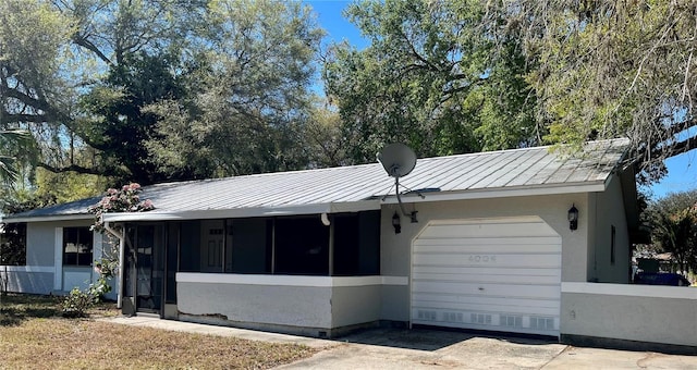 ranch-style house with a garage, metal roof, a standing seam roof, and stucco siding