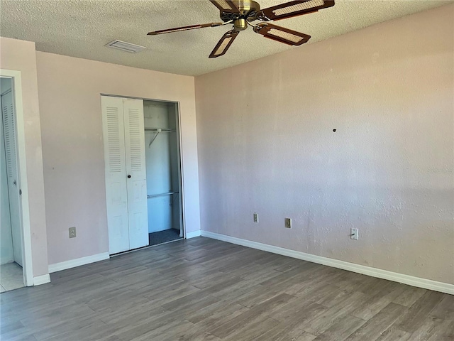 unfurnished bedroom with a closet, visible vents, a textured ceiling, and wood finished floors