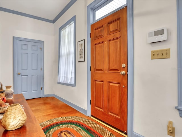 entryway featuring crown molding, light wood-type flooring, and a wealth of natural light